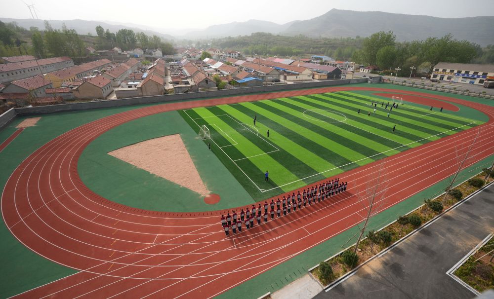 在位于山东潍坊市临朐县石家河村的临朐县弥水教育集团石家河校区,学生在操场塑胶跑道上进行体育锻炼(2025年4月17日摄)。新华社记者 徐速绘 摄