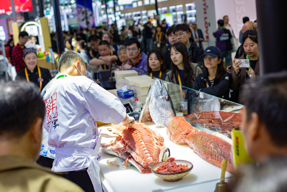 2025年11月7日,在第八届进博会农食产品展区,参观者在一处展台观看开鱼秀。工作人员当场分切一条超过100公斤的金枪鱼。英国奶酪、法国葡萄酒、意大利黑醋、马来西亚榴莲、厄瓜多尔巧克力、新西兰乳制品、阿根廷牛肉……在本届进博会农食产品展区,多款“洋特产”亮相,展商现场加工、制作食品,供参观者品尝。
