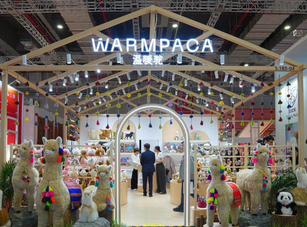 2025年11月5日在第八届进博会消费品展区拍摄的“温暖驼”展台。从秘鲁阿雷基帕的小店,到进博会的展台,再到全球消费者手中,进博会为“温暖驼”带来了巨大的发展机遇。本届进博会,“温暖驼”展位面积已从2018年首届进博会的9平方米拓展至54平方米,并在上海、厦门等地开设6家门店。源自进博会的“温暖驼”订单不仅助力秘鲁200多个家庭脱贫,还倒逼一场“品质革命”,让羊驼玩偶制作对标世界标准。