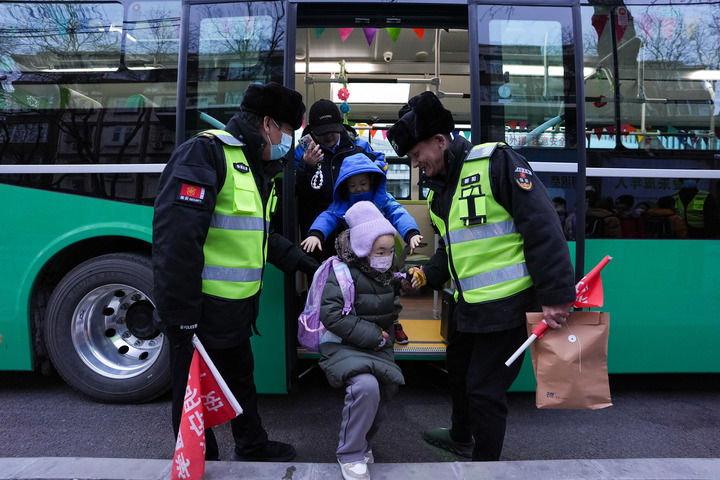 北京公交集团通学368路车停靠在呼家楼中心小学终点站,工作人员引导小学生下车(2024年12月16日摄)。新华社记者 鞠焕宗 摄