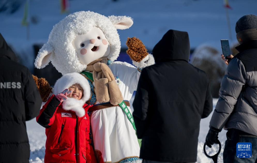 12月21日,游客和第二十一届内蒙古自治区冰雪那达慕开幕式上的卡通人物合影。新华社记者 连振 摄