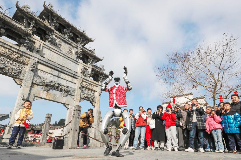 △2026年2月18日,游客在安徽黟县西递古村观看机器人表演。