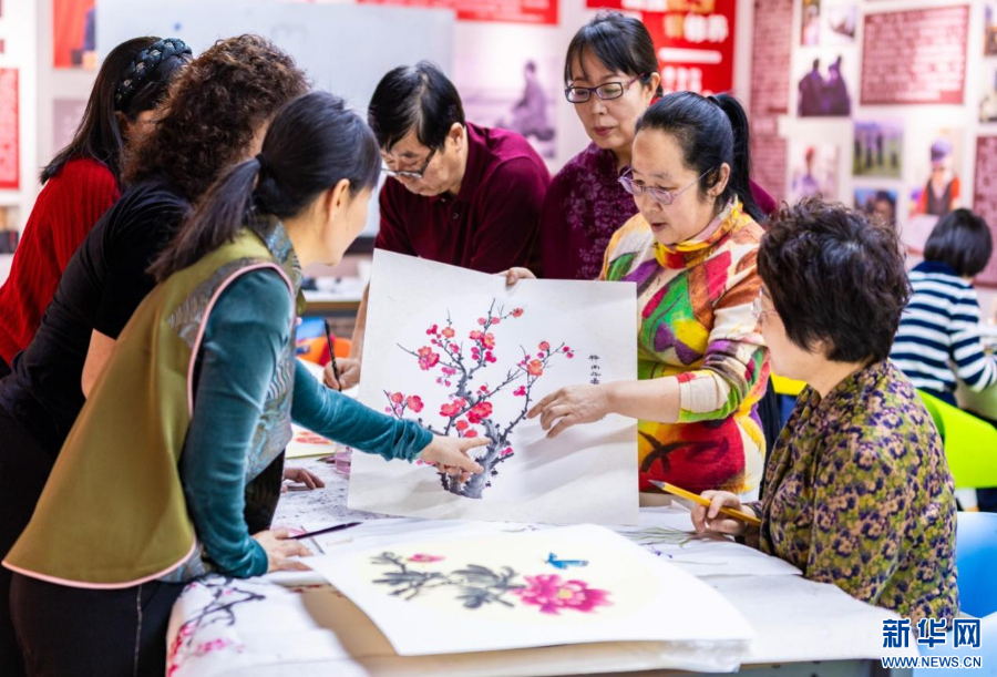 老年学员在呼和浩特市玉泉区老年大学绘画课上交流国画技艺。新华网发(丁根厚 摄)