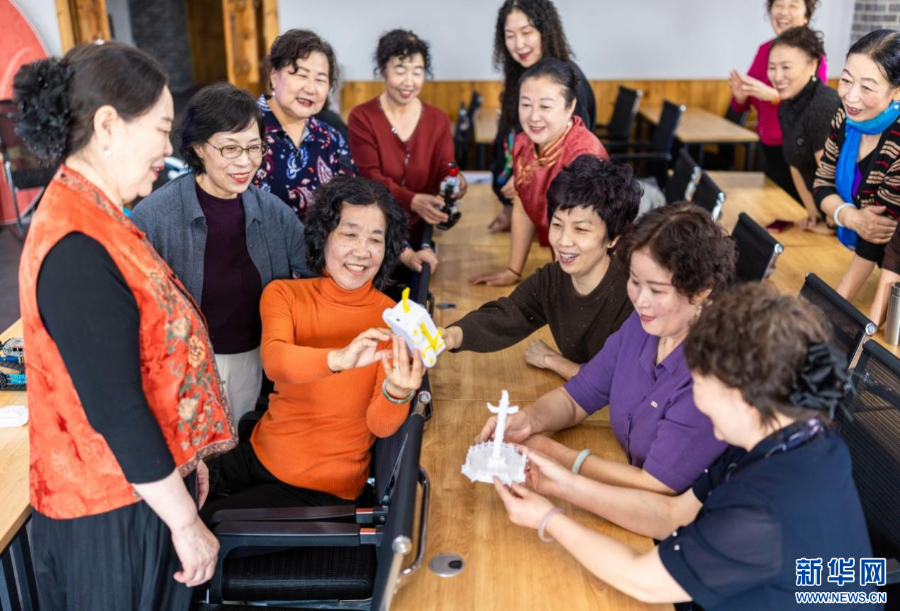 老年学员在呼和浩特市玉泉区老年大学智能应用课上观看3D打印模型。新华网发(丁根厚 摄)