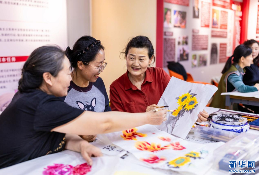 老年学员在呼和浩特市玉泉区老年大学绘画课上交流国画技艺。新华网发(丁根厚 摄)