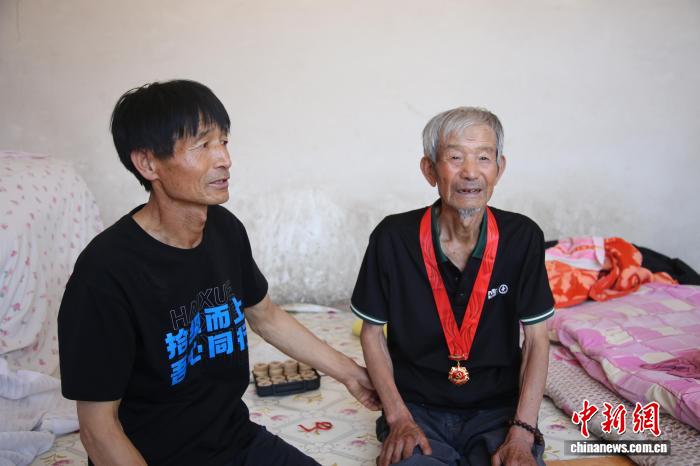 资料图:2025年,段显(图右)荣获“光荣在党50年”纪念章后,与儿子合影。李艳红 摄
