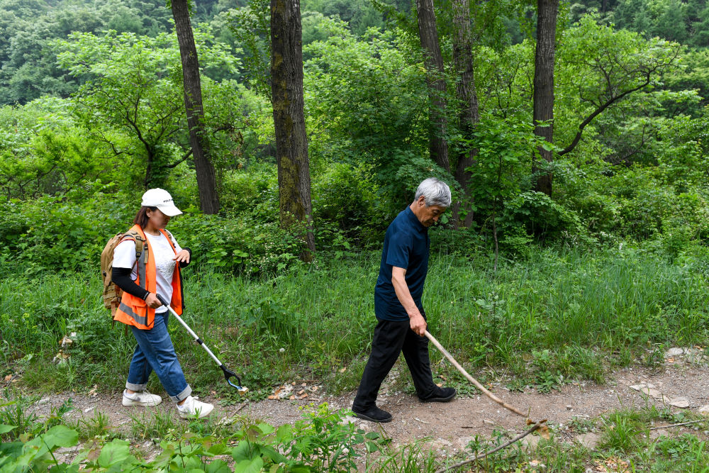 2024年5月23日,在北京市延庆区石峡村,身患听力残疾的长城保护员梅景田(右)和外甥女刘红岩在前往长城的山路上。上世纪80年代初,梅景田开始自发保护长城,已带动许多村民形成保护长城的意识。2025年他获得“全国自强模范”称号。