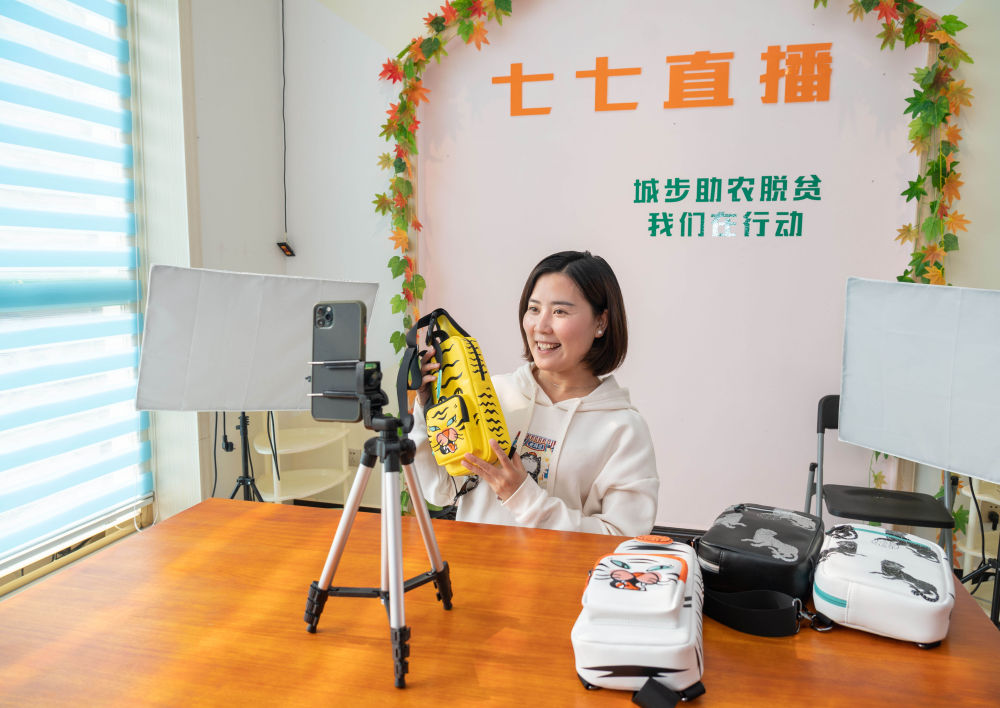 2020年10月13日,在湖南省邵阳市城步县湖南七七科技股份有限公司,残疾青年杨淑亭通过网络销售背包。1991年出生的苗族姑娘杨淑亭因车祸胸部以下高位截瘫,通过不断学习摸索,开办网店并注册了自己的企业,与周边贫困家庭签订合作协议,制作售卖具有民族特色的背包和仿真花卉,带动贫困人员及残疾人就业。