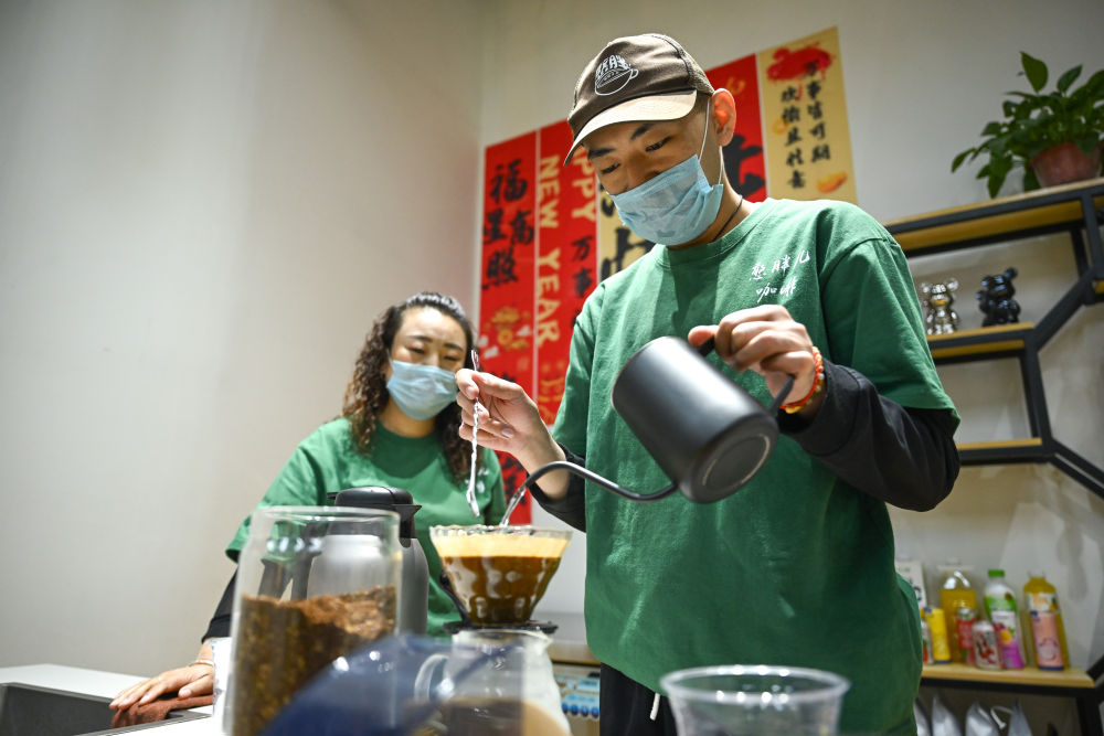 2025年,首家“憨胖儿咖啡”在内蒙古呼和浩特市新城区哲里木路社区开业,为患孤独症和智力残疾的青年提供就业机会,帮助他们融入社会。目前这家公益咖啡馆已在呼和浩特市开设7家门店。这是2026年5月8日,咖啡师小宇(右)在呼和浩特市玉泉区一家憨胖儿咖啡店制作咖啡,他的母亲赵巧花(左)也是店里的一名员工。