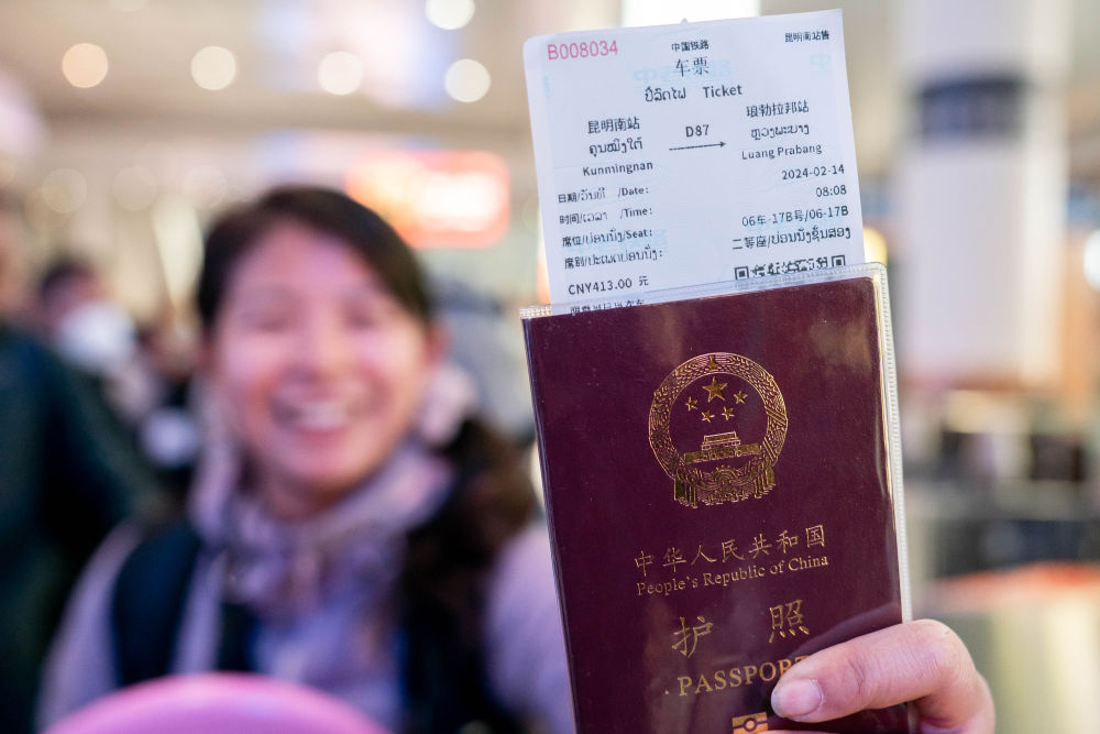 2024年2月14日,在云南昆明乘坐中老铁路国际旅客列车前往老挝的游客展示购买到的车票。中老铁路通车后,不少游客选择乘坐国际旅客列车跨境旅行,推动老挝沿线旅游业发展。