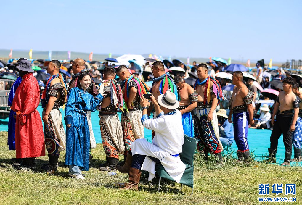 7月19日,游客在搏克比赛待出场队伍前拍照留影。