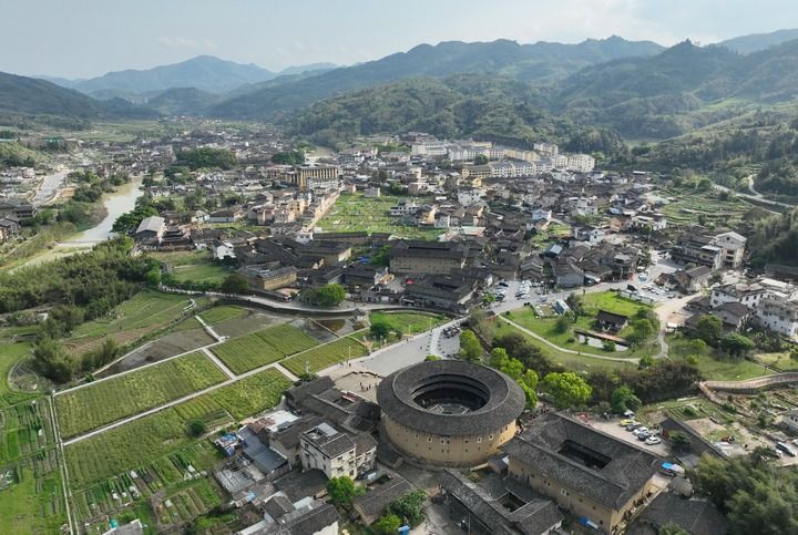 2026年4月9日,游客在福建省漳州市南靖县梅林镇参观怀远楼、和贵楼、长教溪等景点(无人机照片)。新华社记者 林善传 摄