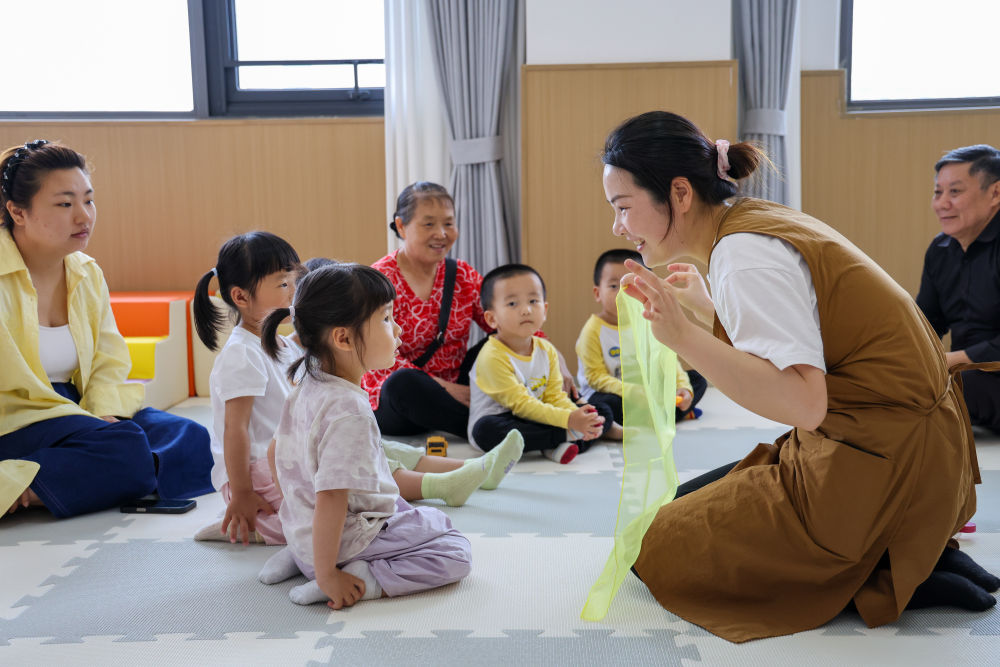 2026年4月15日,在广东省深圳市龙华区民治街道民康社区“一老一小”综合服务站,老师在陪孩子们做游戏。新华社记者 梁旭 摄