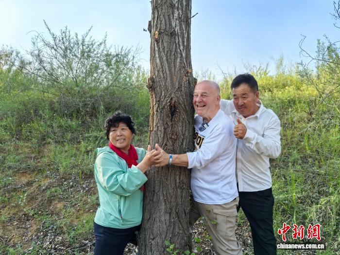 8月24日下午,内蒙古鄂尔多斯市乌审旗,中国“治沙劳模”殷玉珍夫妇和美国友人“赛考斯”(右二)与26年前种下的树合影。 中新社记者 曾玥 摄