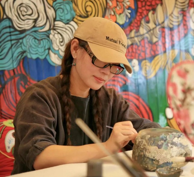 鲁婷正在黄河石上作画。乌海融媒 图